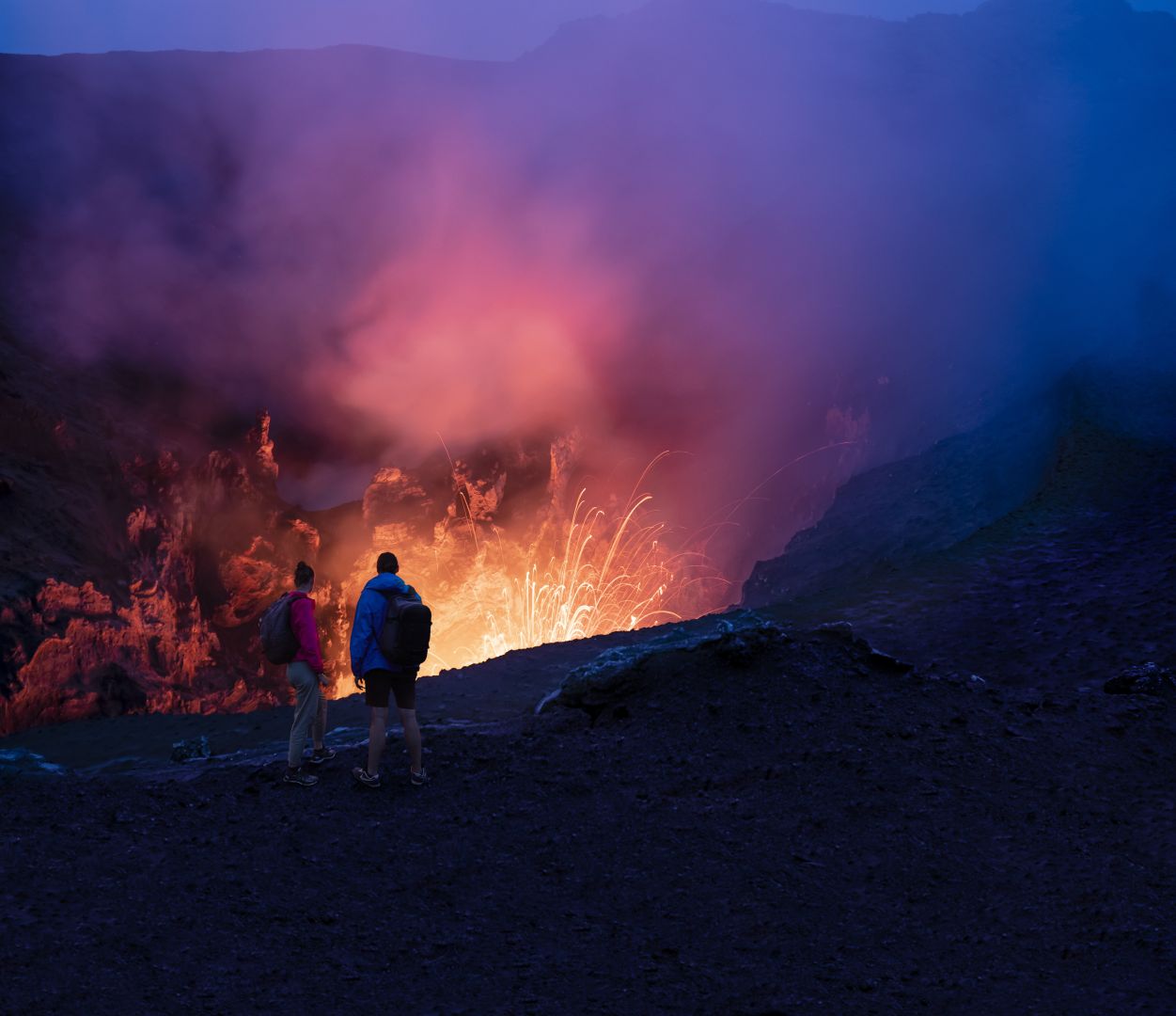 A couple on an evening hike to the summit of Mt Yasur
