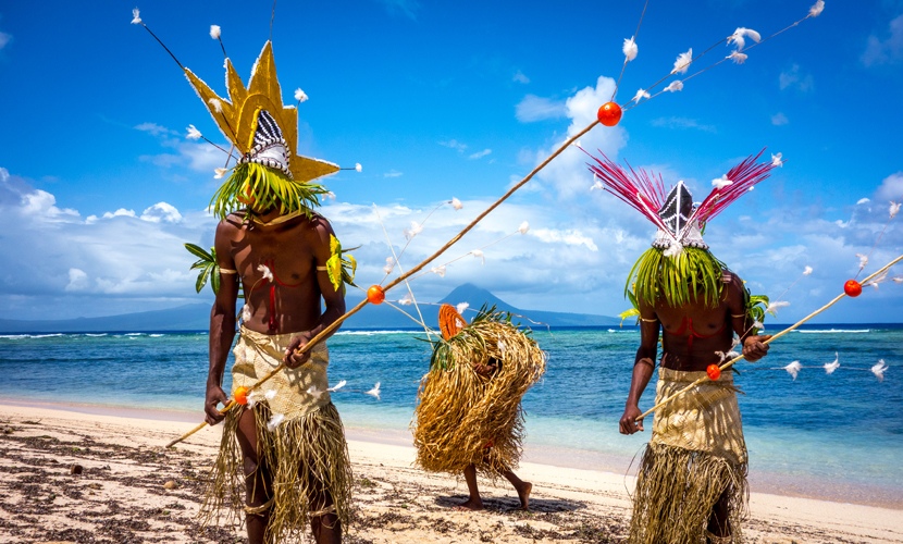 A group of people in traditional dress on a white sandy beach